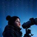 Child looking through a telescope at night
