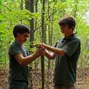 Children learning to build a lean-to shelter in the woods