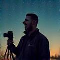 Mark Thompson, an instructor at Threxalimorenta, with a camera and tripod under a starry sky