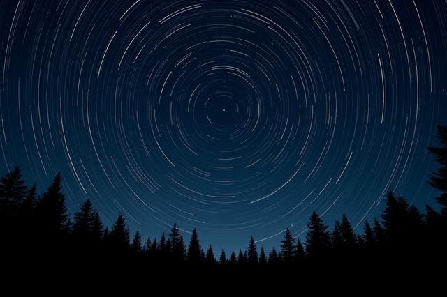 Photograph of star trails over a New Hampshire forest.